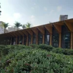 Fachada da Prefeitura de João Monlevade, com edifício de arquitetura moderna, amplas janelas de vidro e jardins na área externa. A imagem representa a sede do Poder Executivo municipal.