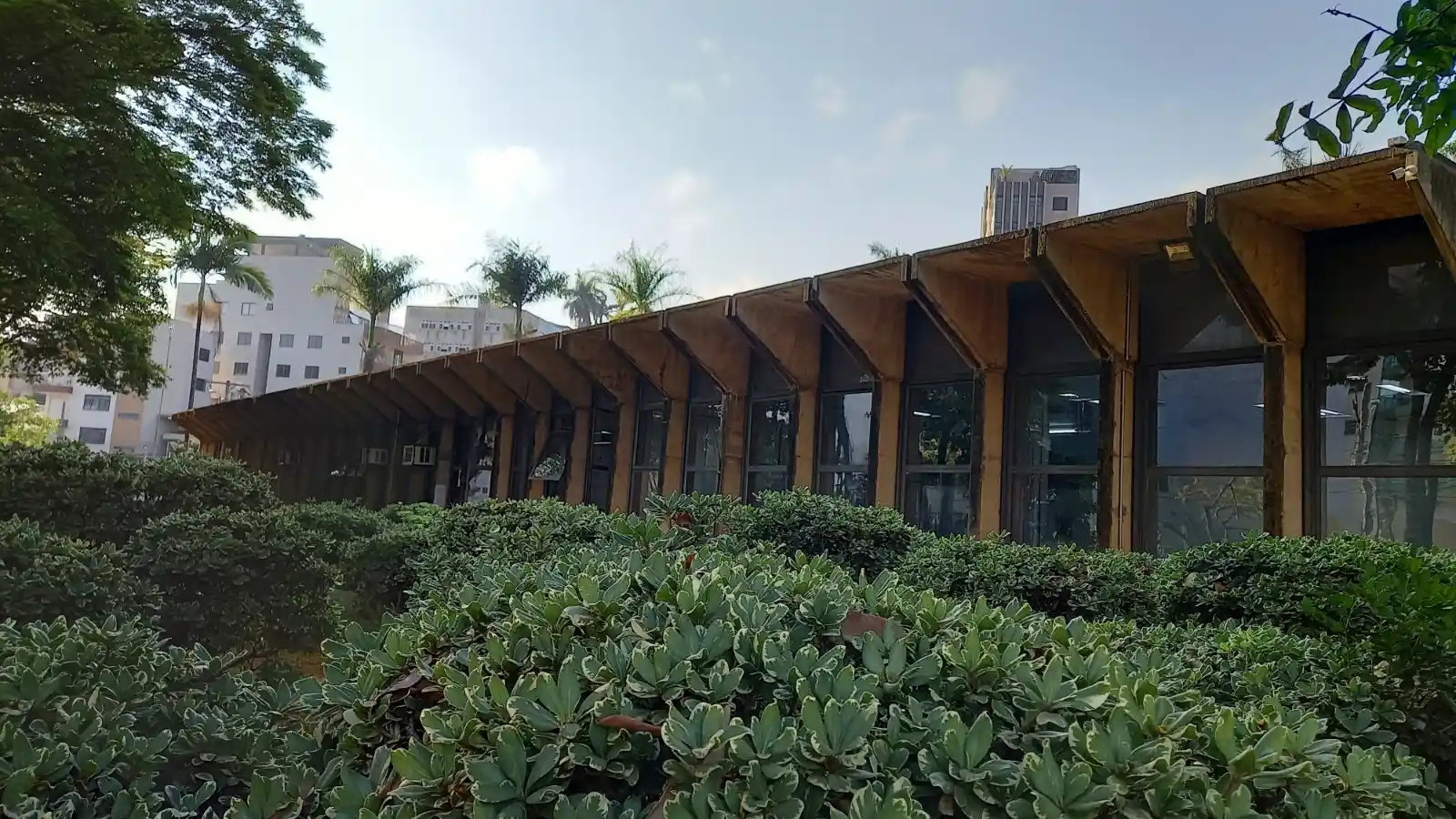 Fachada da Prefeitura de João Monlevade, com edifício de arquitetura moderna, amplas janelas de vidro e jardins na área externa. A imagem representa a sede do Poder Executivo municipal.