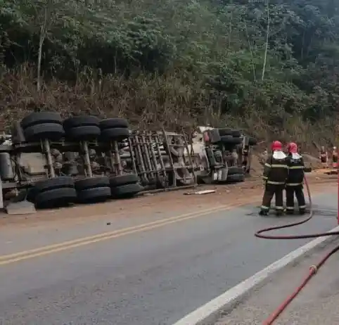 Carreta tombada às margens da BR-381, em Belo Oriente, enquanto bombeiros trabalham no local da ocorrência.
