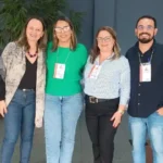 Quatro profissionais da saúde posam para foto durante evento realizado pela Secretaria de Estado da Saúde em Belo Horizonte. O encontro reuniu referências técnicas de IST/AIDS e hepatites virais, incluindo representantes de João Monlevade, para discutir estratégias de acolhimento e assistência aos usuários da rede pública de saúde.