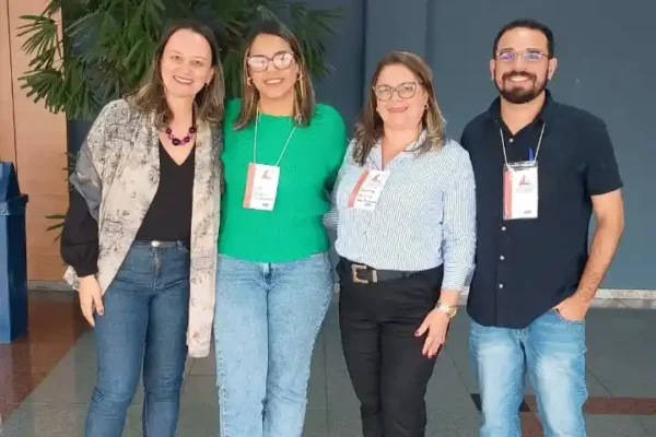 Quatro profissionais da saúde posam para foto durante evento realizado pela Secretaria de Estado da Saúde em Belo Horizonte. O encontro reuniu referências técnicas de IST/AIDS e hepatites virais, incluindo representantes de João Monlevade, para discutir estratégias de acolhimento e assistência aos usuários da rede pública de saúde.