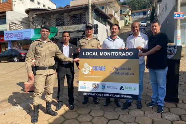 Autoridades municipais, policiais militares e representantes da ACIARP posam em uma rua do Centro de Rio Piracicaba segurando uma placa do Projeto Vigilância Colaborativa. A ação marca a ampliação do sistema de videomonitoramento e reforça as medidas de segurança pública no município.