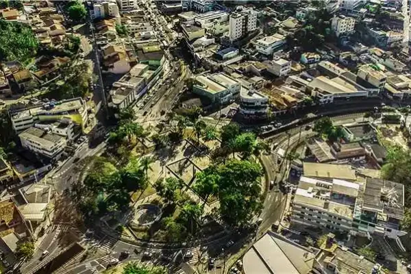 Imagem aérea do centro de Itabira, com ruas, prédios, praças e áreas arborizadas vistas de cima. A fotografia ilustra o cenário urbano da cidade e o contexto de obras públicas e projetos de infraestrutura voltados ao desenvolvimento municipal.