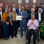 Autoridades, familiares e convidados posam para foto durante solenidade na Câmara Municipal de João Monlevade. Ao centro, o homenageado Antônio Sebastião Alves Linhares, conhecido como Nozinho, recebe certificado de Moção de Aplausos. A cerimônia reconheceu sua trajetória profissional e sua atuação comunitária, incluindo a participação na fundação da Colônia Bom Samaritano.