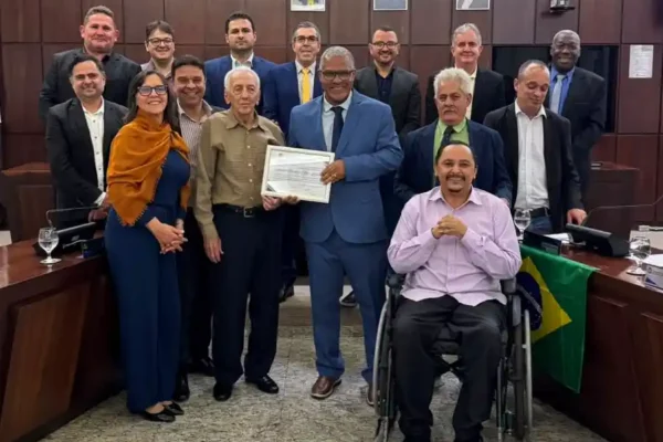Autoridades, familiares e convidados posam para foto durante solenidade na Câmara Municipal de João Monlevade. Ao centro, o homenageado Antônio Sebastião Alves Linhares, conhecido como Nozinho, recebe certificado de Moção de Aplausos. A cerimônia reconheceu sua trajetória profissional e sua atuação comunitária, incluindo a participação na fundação da Colônia Bom Samaritano.