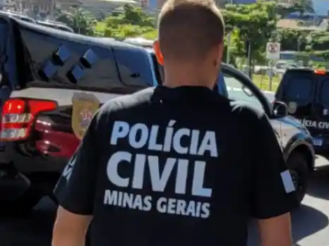 Policial com uniforme da Polícia Civil de Minas Gerais caminha próximo a viaturas oficiais durante uma operação. A fotografia ilustra uma ação policial relacionada à captura de um investigado e ao cumprimento de mandado de prisão.