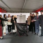 Representantes do Ministério Público de Minas Gerais (MPMG) participam do descerramento da placa de inauguração da nova sede das Promotorias de Justiça de João Monlevade. A cerimônia ocorre em frente à placa comemorativa, marcando a entrega da nova estrutura destinada ao atendimento da população e às atividades do Ministério Público.