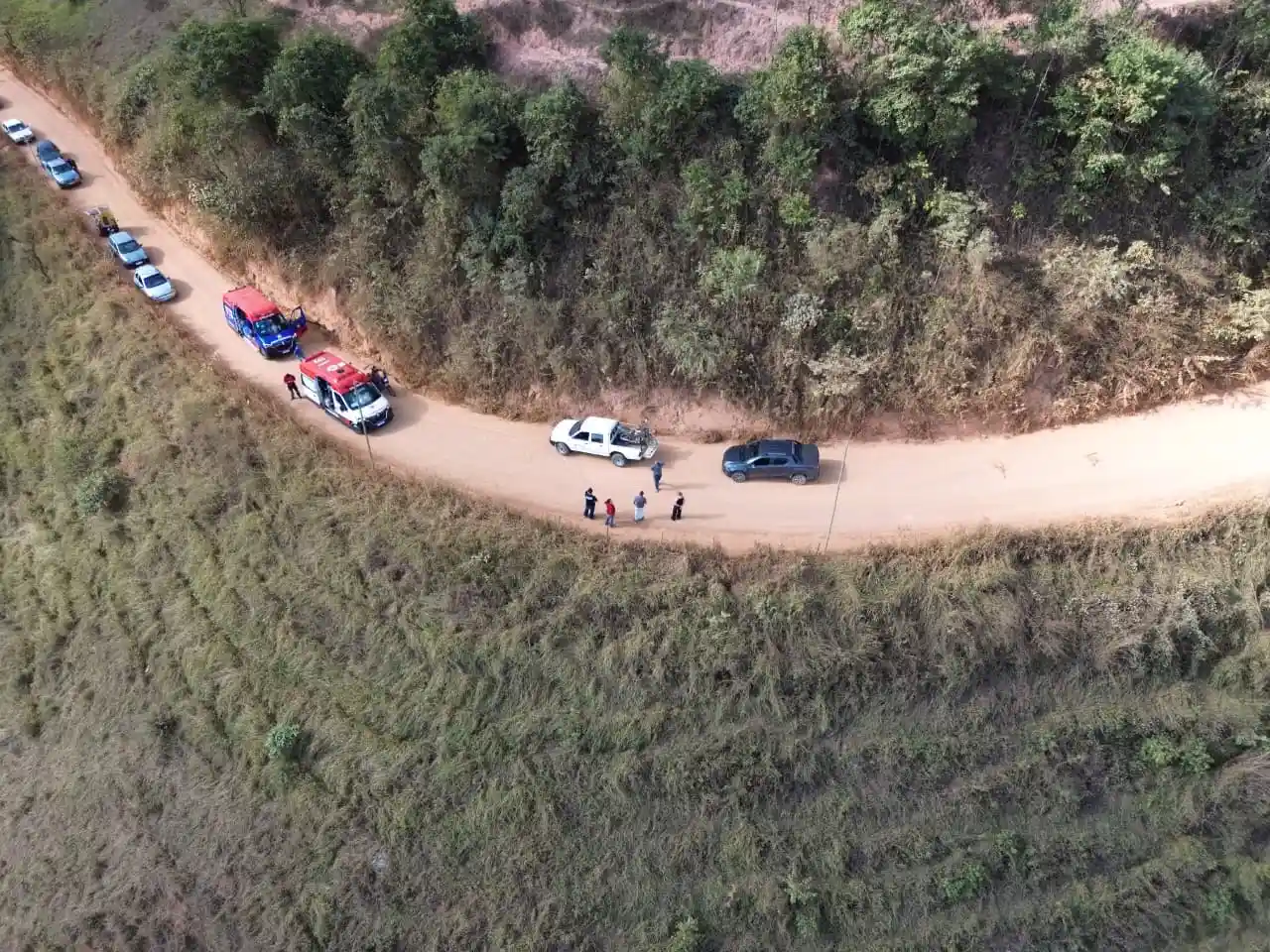 Imagem aérea mostra equipes do SAMU e dos Bombeiros Voluntários atendendo uma ocorrência em uma estrada de terra em São Domingos do Prata. Viaturas de resgate, carros parados e pessoas estão no local. O motociclista ferido foi estabilizado e levado ao Hospital Margarida, em João Monlevade, para avaliação médica.