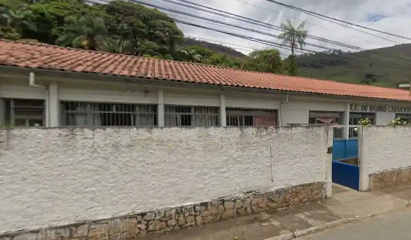Fachada da Escola Estadual do Bairro Laranjeiras, em João Monlevade, com muro branco e portão azul. A SEE-MG confirmou o fechamento definitivo da unidade após reorganização da rede estadual de ensino.